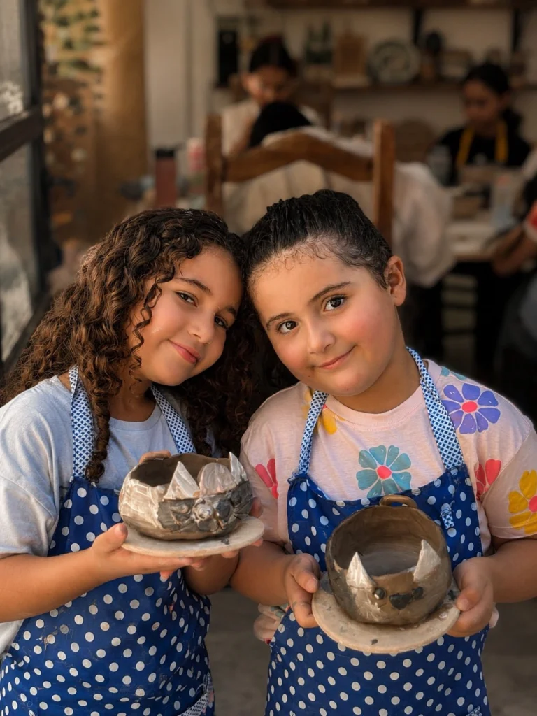 طفلتان تعرضان قطعتيهما الفخاريتين
